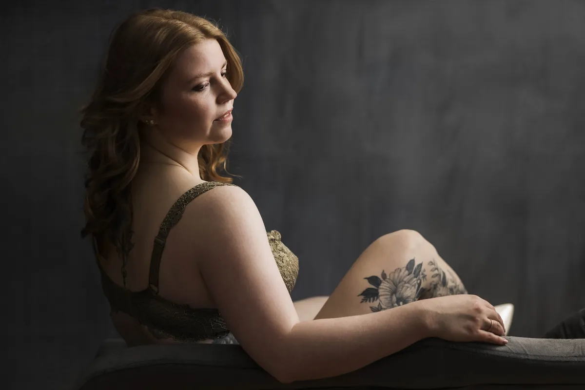 Frau im Profil in goldener Spitzenwäsche, seitliches Streiflicht, Blumentattoo sichtbar – Boudoir-Fotografie Atelier Chur