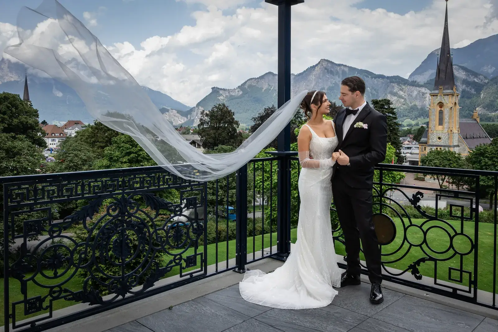 Brautpaar auf dem Balkon mit wehendem Schleier, Kirche und Bergen in Bad Ragaz