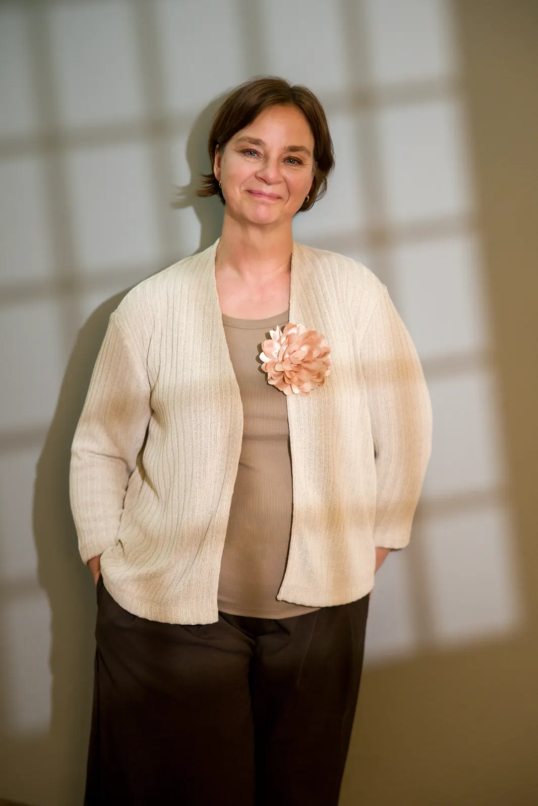 Business-Portrait im hellen Cardigan vor heller Wand