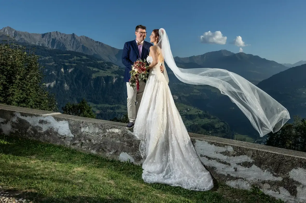 Brautpaar mit wehendem Schleier vor dem Bündner Bergpanorama