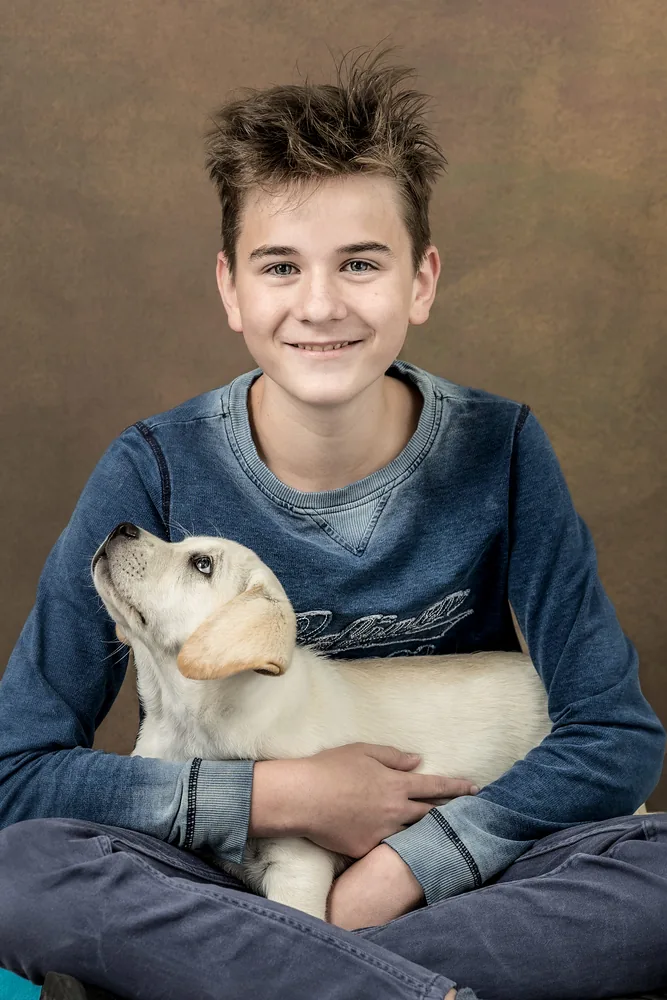 Junge mit seinem Welpen auf dem Schoss, herzliche Verbindung – Familien-Portrait Atelier Chur
