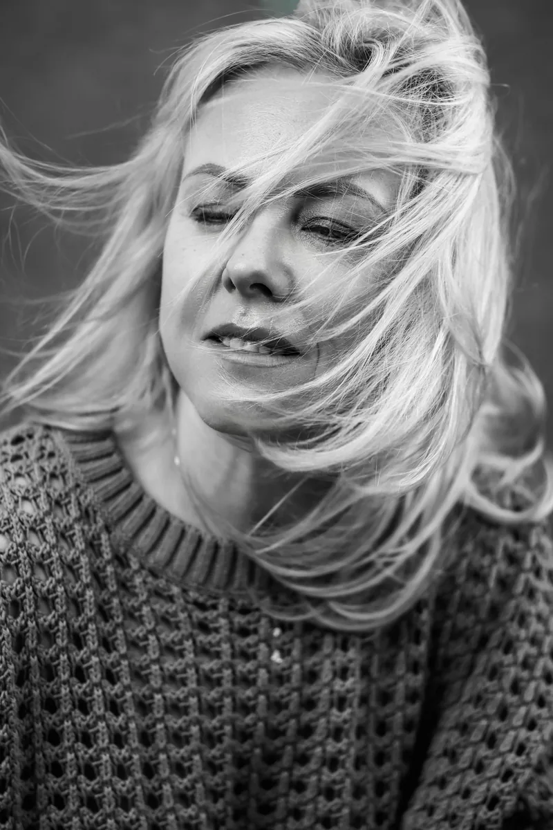 Frau im Wind, Haare vor dem Gesicht, ruhiger Moment – Portrait Atelier Chur