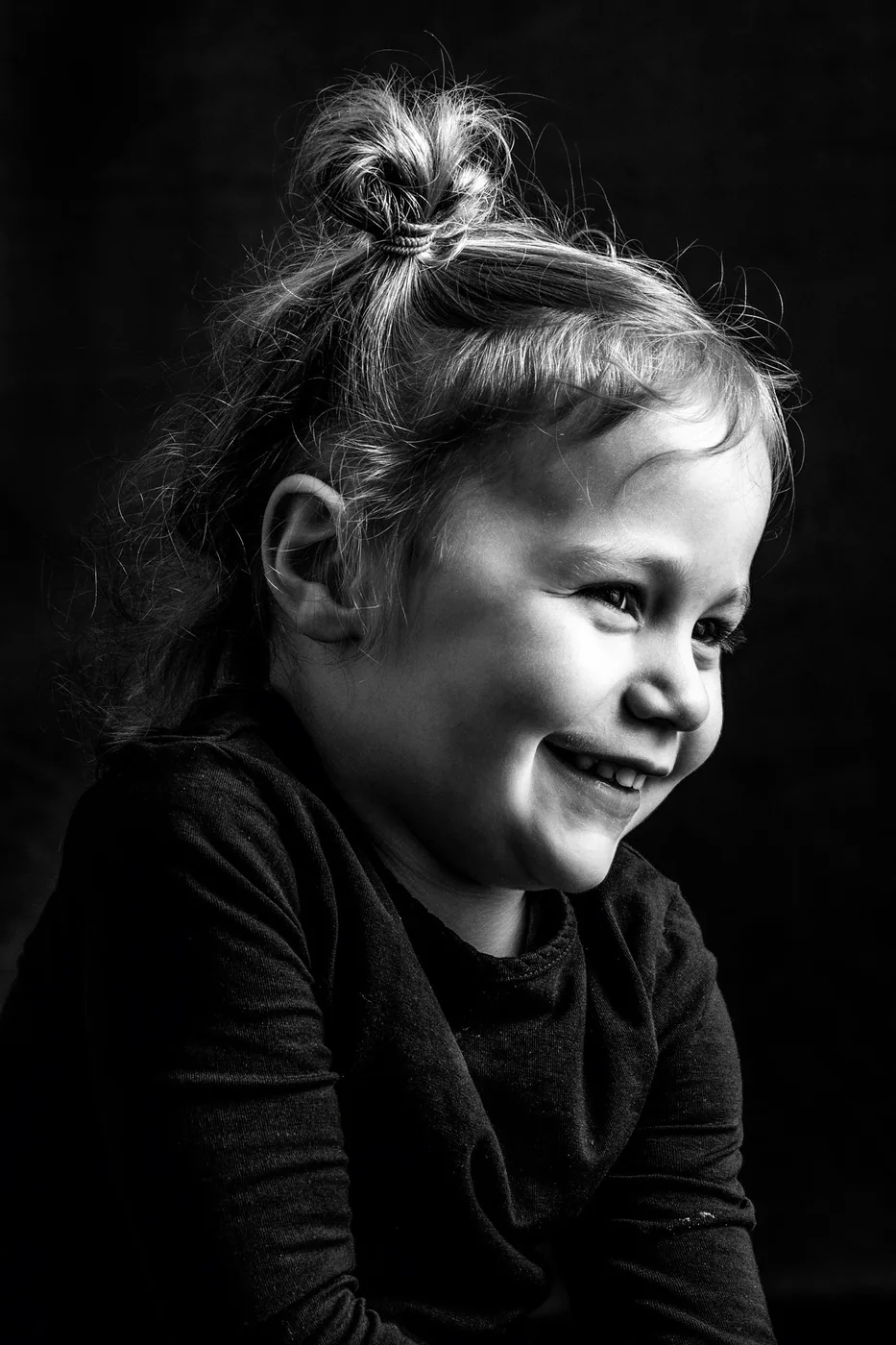 Kleines Mädchen lacht herzlich im Portrait, dunkler Hintergrund – Familien-Portrait Atelier Chur